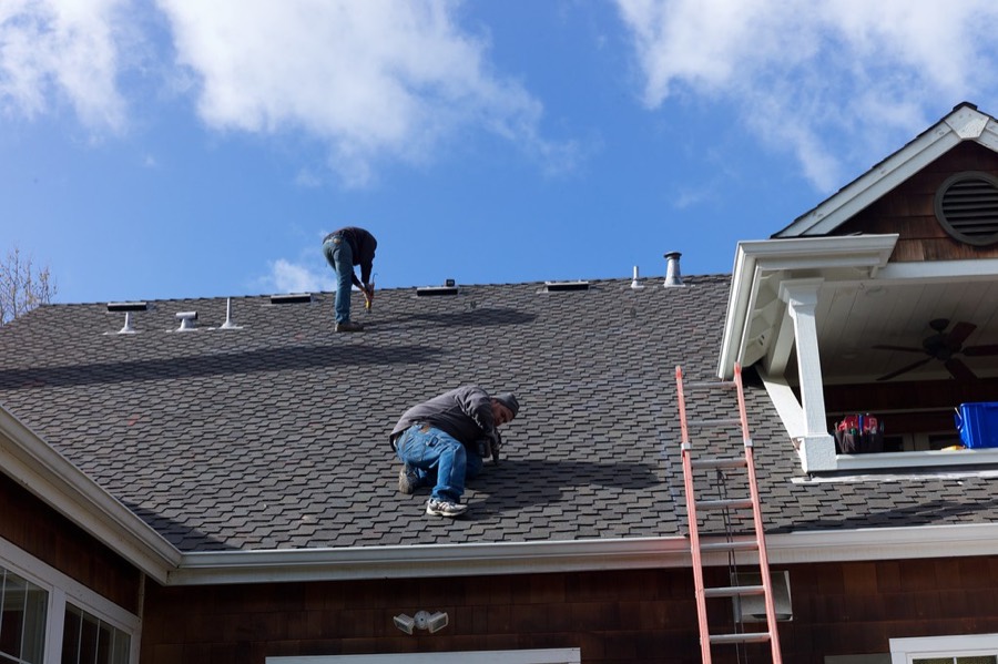 Roofers installing shingles on a home